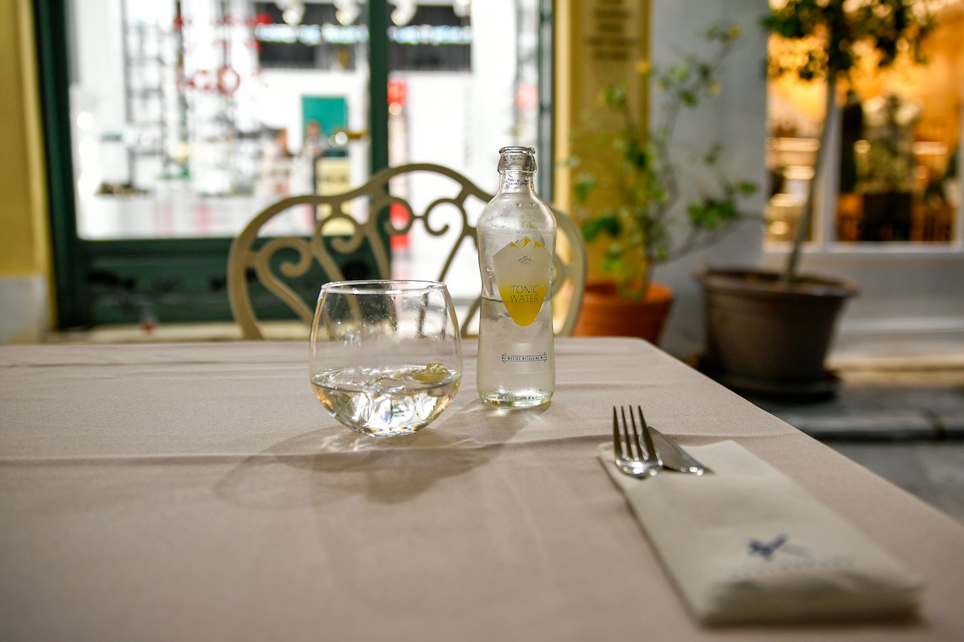 Single place setting with glass and cutlery on a white tablecloth